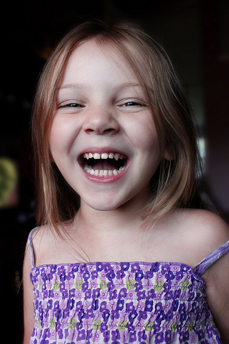 pedo-gum-disease-your-child A little girl is smiling while holding a tv remote.