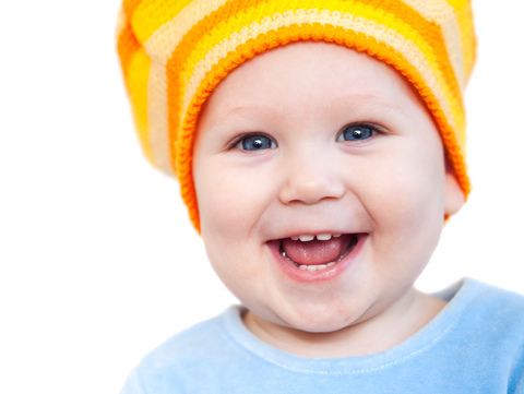 baby-teeth A baby wearing a yellow and orange striped hat.