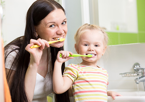 brushing_child A mother and child brushing their teeth in a bathroom.