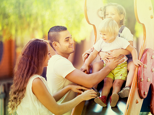 A family is playing on a slide in a park.