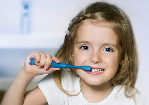 A little girl is brushing her teeth.