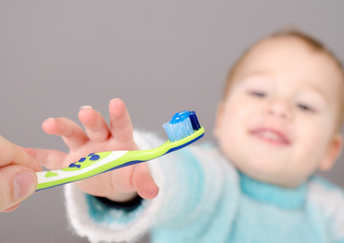 A child is holding a toothbrush.