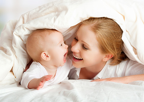 cleaning_babys_teeth A baby lying under a blanket.