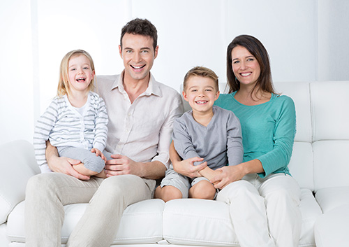 A family sitting on a white couch.
