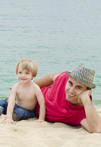 A man and a child laying on the beach.