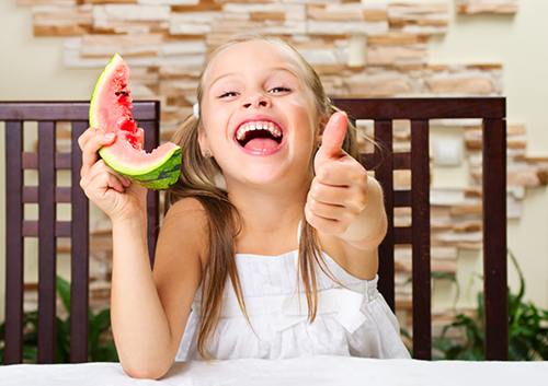 five-fun-snacks_44949130 A girl is eating a slice of watermelon.