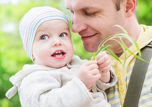 five-tips-tots-dentist A man holding a baby while holding a plant.