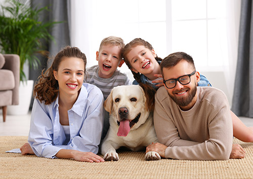 furry_friend A family posing with a dog in a living room.