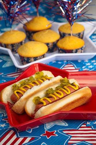 holiday-fourth-of-july Hot dogs and cupcakes on a red plate.