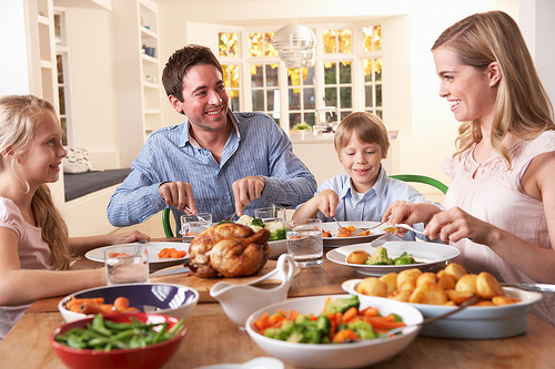 A family sitting at a table eating dinner.