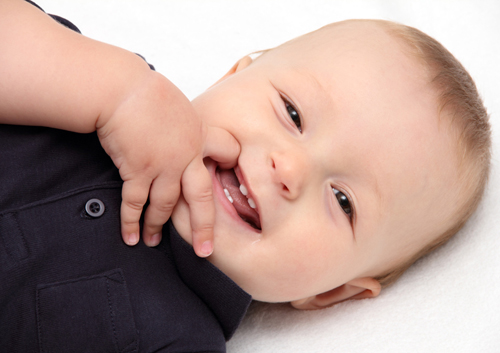 A baby is laying on a white blanket.