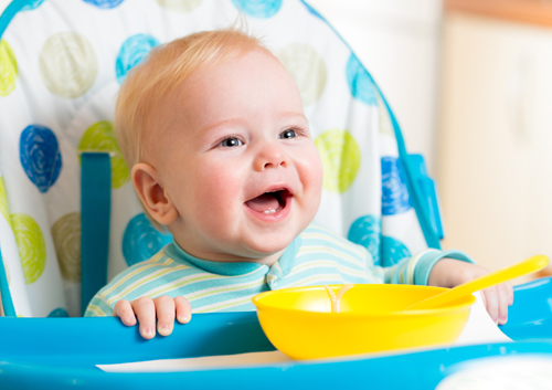 make-childs-diet-safe-for-teeth A baby is sitting in a high chair with a bowl.