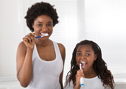 A woman and a girl brushing their teeth.