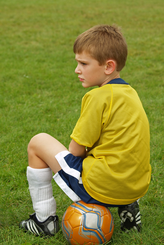 ortho-spring-sports A young boy sitting on a soccer ball.