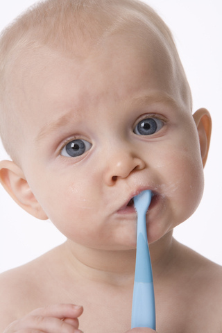 pedo-baby-brushing A baby is brushing his teeth with a blue toothbrush.