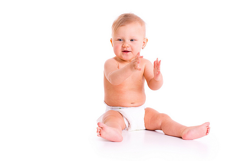 pedo-baby-sitting A baby in a diaper sitting on the floor.