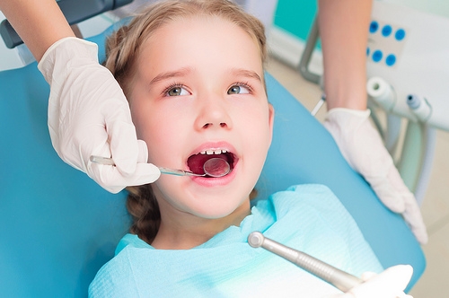 pedo-exam A young girl is getting her teeth checked by a dentist.
