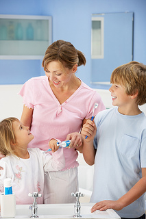 A woman and a child brushing their teeth in a bathroom.