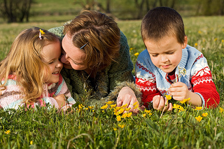 A woman and two children laying in a field.