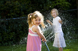 pedo-kidsplaying-smiling Two girls playing with a water hose.