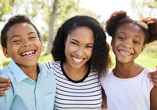 Three children and their mother smiling in a park.