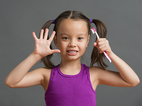 when_dental_care_xl_87216021 A little girl holding a toothbrush.